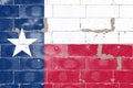 The national flag of the US state of Texas is blue in red and white with a star painted on an old brick wall with cracked paint in Royalty Free Stock Photo