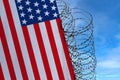 National flag of USA on concrete wall, barbed wire fence, concept of prison, symbol of police state, territory border,