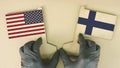 Holding flags of the USA and Finland made of recycled paper on the cardboard table