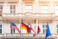 National flags on old building facade in european city. Flags of USA, Germany, Austria, European Union and folded Great Britain Royalty Free Stock Photo