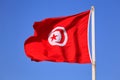 The national flag of Tunisia against the blue sky