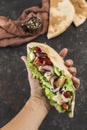 National Greek fast food pita with chicken and fresh vegetables in the male hand of the chef on a dark background Royalty Free Stock Photo