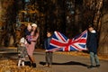 National holiday of United Kingdom. Family with british flags in autumn park. Britishness celebrating UK. Mother with four kids