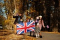 National holiday of United Kingdom. Large family with four kids holding british flags in autumn park. Britishness celebrating UK