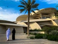 National museum of Qatar with unidentified Arabic couple walking, Doha. The museum is shaped like a desert rose and is newly build