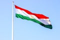 National red, white and green flag of Tajikistan on the flagpole against the blue sky. Royalty Free Stock Photo