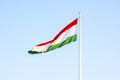 National red, white and green flag of Tajikistan on the flagpole against the blue sky. Royalty Free Stock Photo