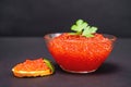 National Russian holiday delicacy - red salmon caviar in glass bowl and on piece of bread decorated with fresh parsley