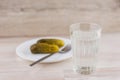 National trait is unhealthy:faceted glass Russian vodka on a white table, a couple of cucumbers laying on the plate, the fork is Royalty Free Stock Photo