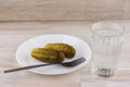 National trait is unhealthy:faceted glass Russian vodka on a white table, a couple of cucumbers laying on the plate, the plug is Royalty Free Stock Photo