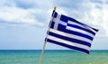 National waving Greek flag and mediterranean sea. Blue sky and Greece flag as background aegean sea. Greece flag is flying. Royalty Free Stock Photo