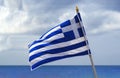 National waving Greek flag and mediterranean sea. Blue sky and Greece flag as background aegean sea. Greece flag is Royalty Free Stock Photo