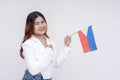 A nationalistic young woman holding one hand to her chest and holding a Philippine flag while smiling at the camera. Isolated on a