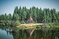 Native American tipi reflecting in the lake