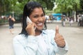 Native american woman at phone in a park showing thumb
