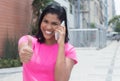 Native american woman at phone showing thumb in city Royalty Free Stock Photo