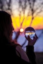 Native Girl looking into Crystal Ball on the Shore of a frozen Lake with a Magical Sunset Royalty Free Stock Photo