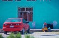 Native Indigenous old lady in traditional dress in colorful city street with car, in Mexico, America