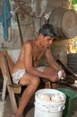 Native senior man cleaning slicing fresh coconut for production