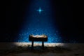 Nativity of Jesus, empty manger at night with bright lights.