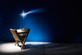 Nativity of Jesus, empty manger at night with bright lights.