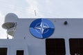 NATO Joint Military Symbology, a dark blue field charged with a white compass rose emblem, with four white lines radiating from