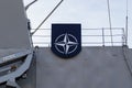 NATO Joint Military Symbology, a dark blue field charged with a white compass rose emblem, with four white lines radiating from