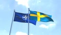 NATO and Sweden flags waving against blue sky.