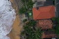 Natural aerial drone bird view day shot of the sea shore with beautiful villas, green trees, yellow sand and big white waves and