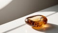 Natural amber stone glistening under soft light on a white surface. Royalty Free Stock Photo