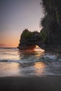 Natural arch. Batu Bolong temple on the rock during sunset. Seascape background. Motion milky waves on black sand beach. Copy Royalty Free Stock Photo