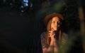 Natural authentic young woman illuminated by sunset light in dark forest. Eco lifestyle