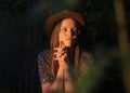 Natural authentic young woman illuminated by sunset light in dark forest. Eco lifestyle