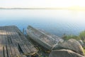 Natural autumn landscape with inverted boat on lakes shore. Fishing concept. Rusty ancient boat at old pier Royalty Free Stock Photo