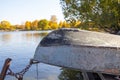 Natural autumn landscape with inverted boat on lakes shore. Fishing concept. Rusty ancient boat at old pier Royalty Free Stock Photo