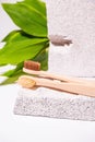 Natural background with bamboo toothbrush, green leaves and white textured stone. Still life wallpaper. Space for text. Zero waste