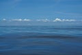 Natural background scene of gradient blue sky horizon and low raining white cloud above deep blue sea moving water ripple Royalty Free Stock Photo