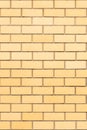The natural background of the wall is made of yellow finishing bricks. Smooth brickwork of a modern building. A vertical fragment