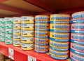 Natural Balance brand cat food tins in various flavors stacked up on a market shelf.