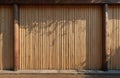 Natural bamboo wall texture with vertical stalks. Shadows from leaves create an abstract pattern. Dark wood beams frame textured Royalty Free Stock Photo