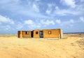 Off-road Aruba. Amazing sand desert landscape with some building on blue sky and white clouds background. Royalty Free Stock Photo