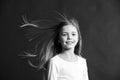 Natural beauty. Girl kid long hair flying in air, black background. Child with natural beautiful healthy hair. Quick