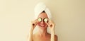 Natural beauty portrait of happy smiling young caucasian woman covers her eyes holds slices of cucumber while drying wet hair with