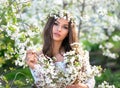 Natural beauty pretty woman with wreath on her head and bouquet of cherry branches in the summer garden, enjoying the blooming Royalty Free Stock Photo