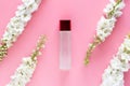 Natural beauty skincare product. luxury cosmetic bottle container with white spring flower herbal on pastel pink background.