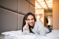 Young pretty woman looking at camera and smiling while lying on the bed at home Royalty Free Stock Photo