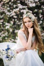 Natural beauty young woman in white dress with a bouquet of wild flowers in a spring blooming garden Royalty Free Stock Photo