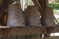 Natural straw hives for bees, built three in a row next to each other on a wooden table.