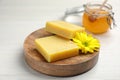 Natural beeswax and flower on white wooden table