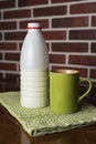 Natural bio milk product. Half bottle of natural milk, kefir and green mug, on a beautiful light green color napkin, wooden table